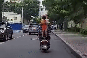 Cho bé gái 'làm xiếc' trên xe máy, tài xế bị chỉ trích